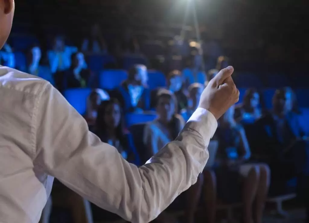 rear view of caucasian businessman giving presentation in front of audience in auditorium rear view of caucasian businessman giving presentation in front of audience in auditorium